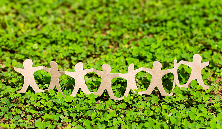 Paper figures showing leadership on green backdrop